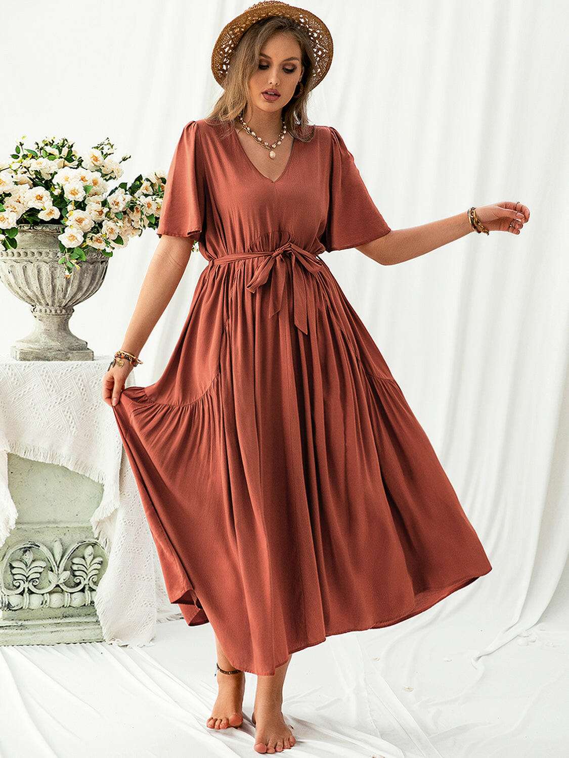 Plus size rust-colored V-neck midi dress with flutter sleeves and a tied waist belt