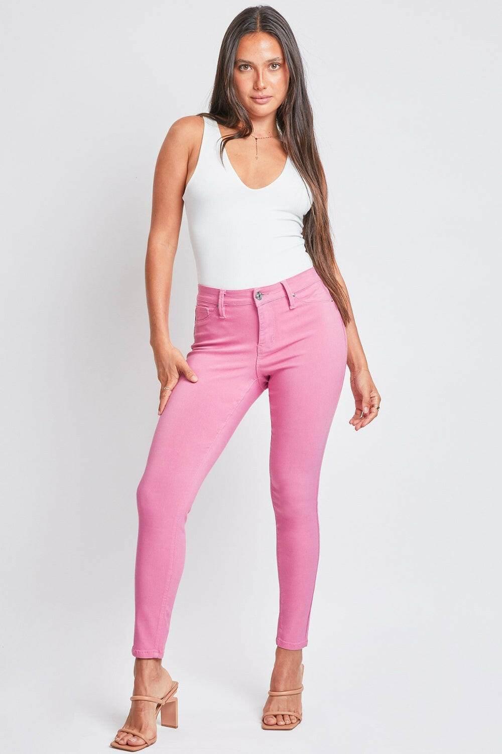 Woman wearing pink YMI Jeanswear hyperstretch mid-rise skinny pants and white tank top