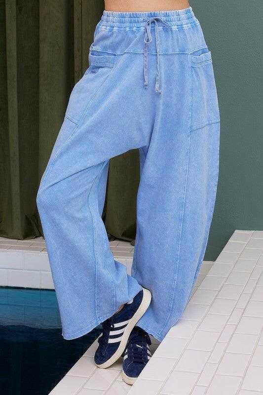 Light blue mineral wash elastic waist barrel leg baggy pants with drawstring and pockets, styled with sneakers.
