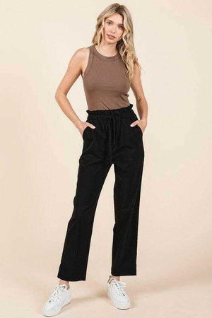 Woman wearing black Mittoshop paperbag waist tapered straight pants with brown sleeveless top and white sneakers
