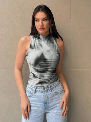 Woman wearing printed mock neck ruched tank top paired with light blue jeans.