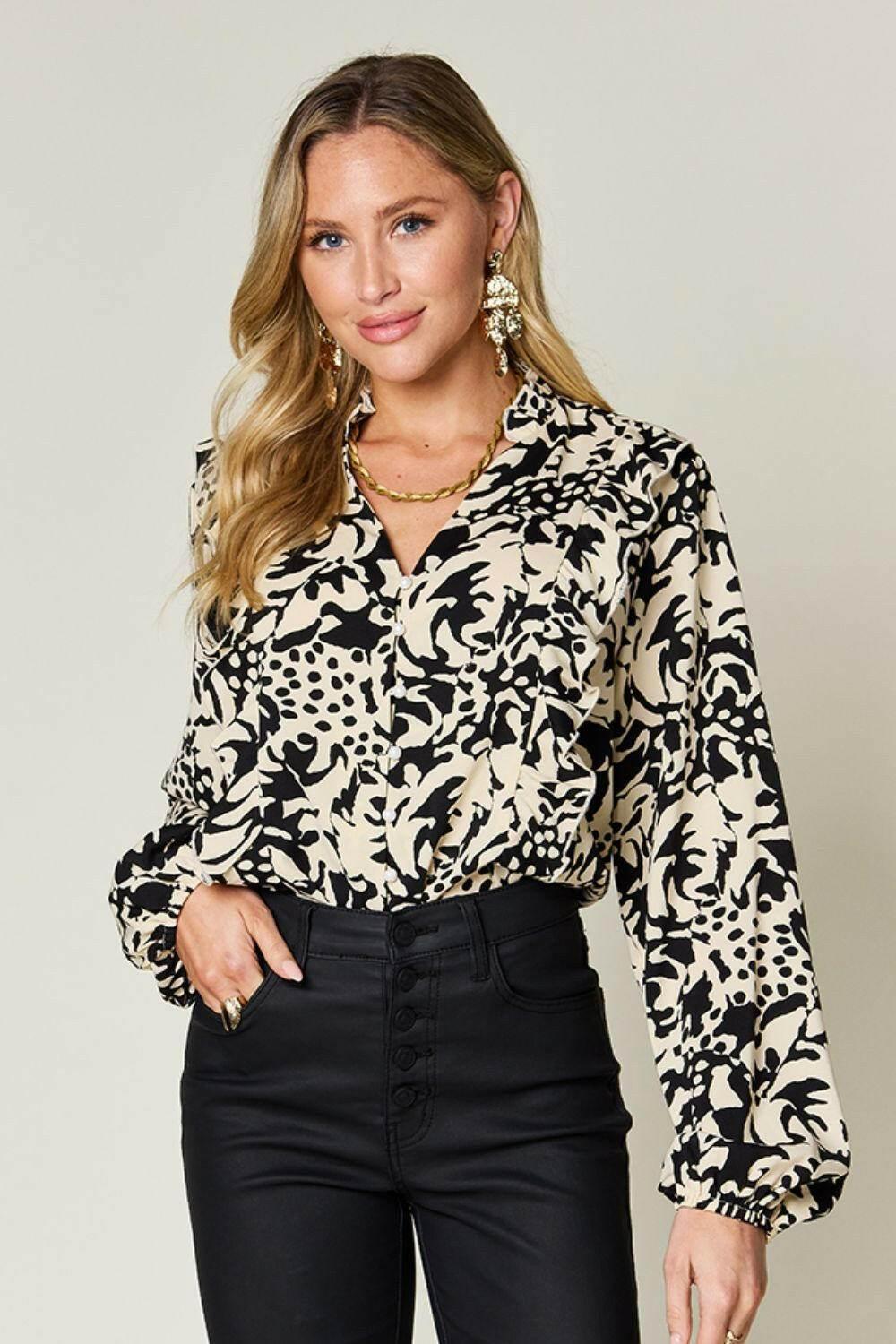 Woman wearing Double Take full size printed ruffle trim balloon sleeve shirt with black and beige abstract pattern and high-waisted black pants