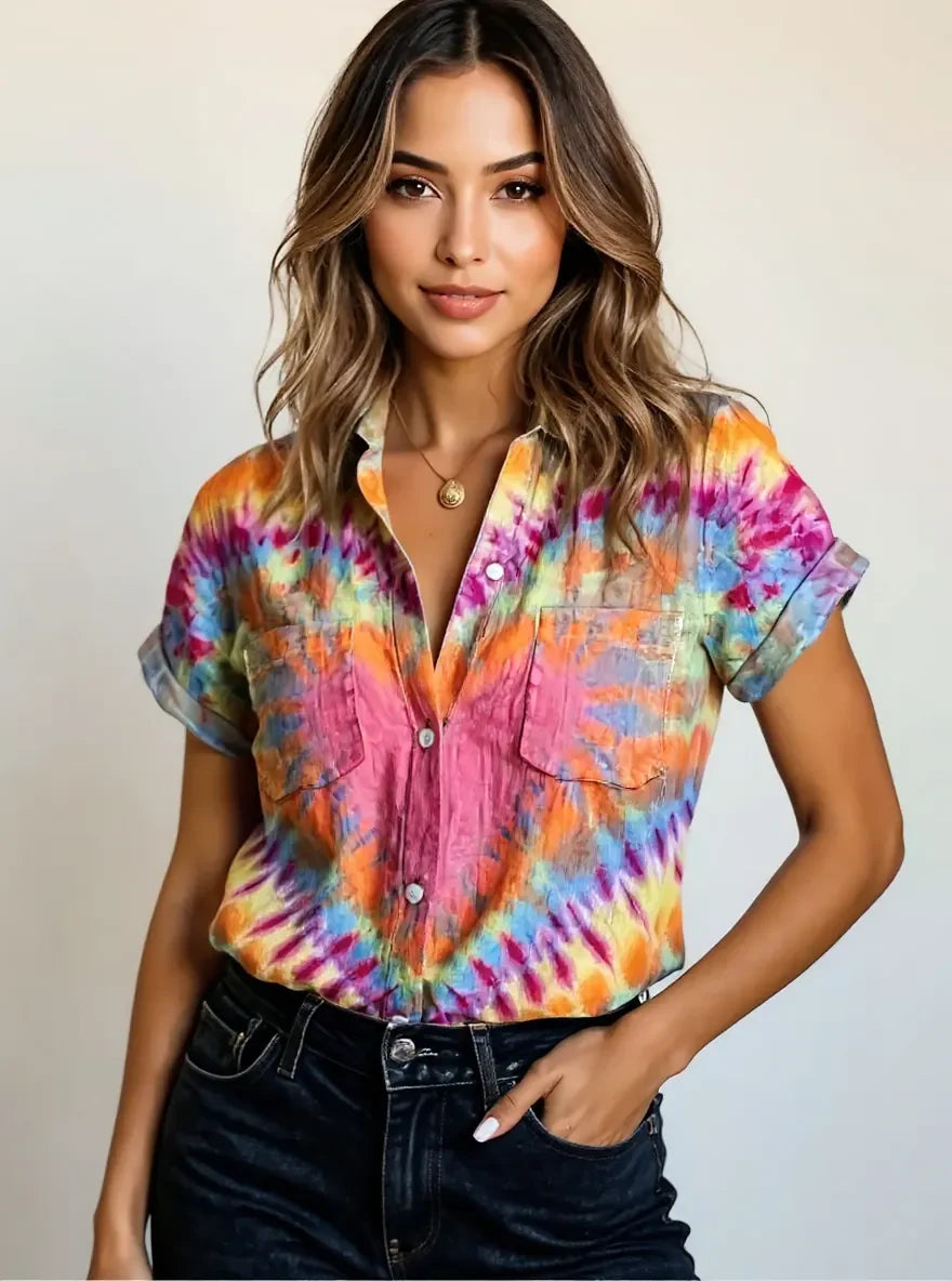 Woman wearing a colorful tie-dye short sleeve button-up shirt with pockets and rolled sleeves