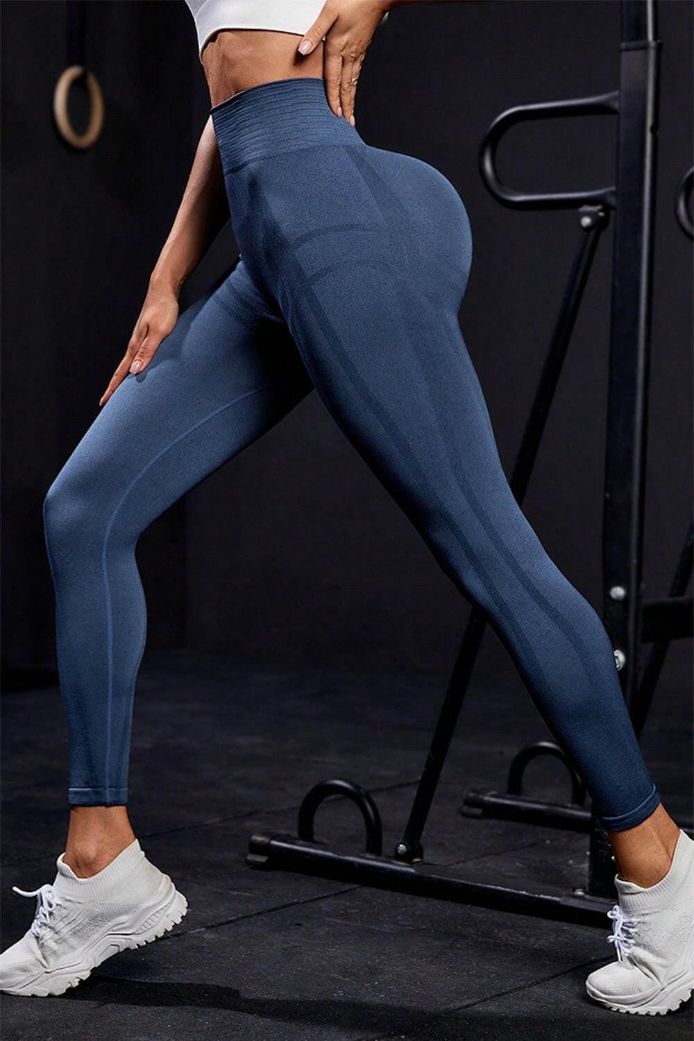 Woman wearing navy wide waistband high waist leggings stretching in gym with white sneakers