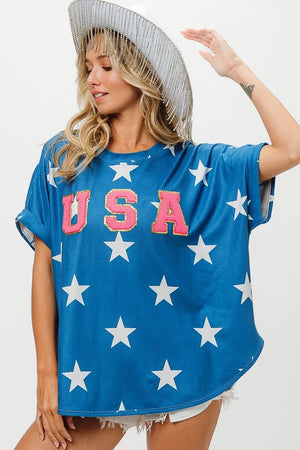 Blue BiBi Fourth Of July Star Knit T-Shirt with white stars and glittery pink USA letters worn with white hat and shorts