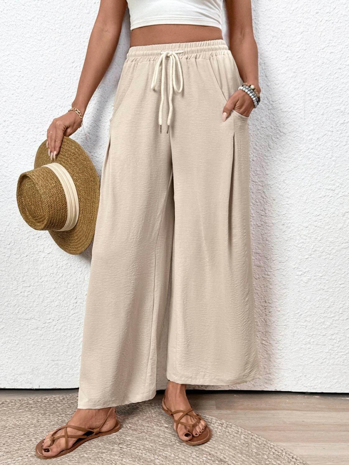 Beige Perfee Drawstring Wide Leg Pants with pockets styled with sandals and holding a straw hat