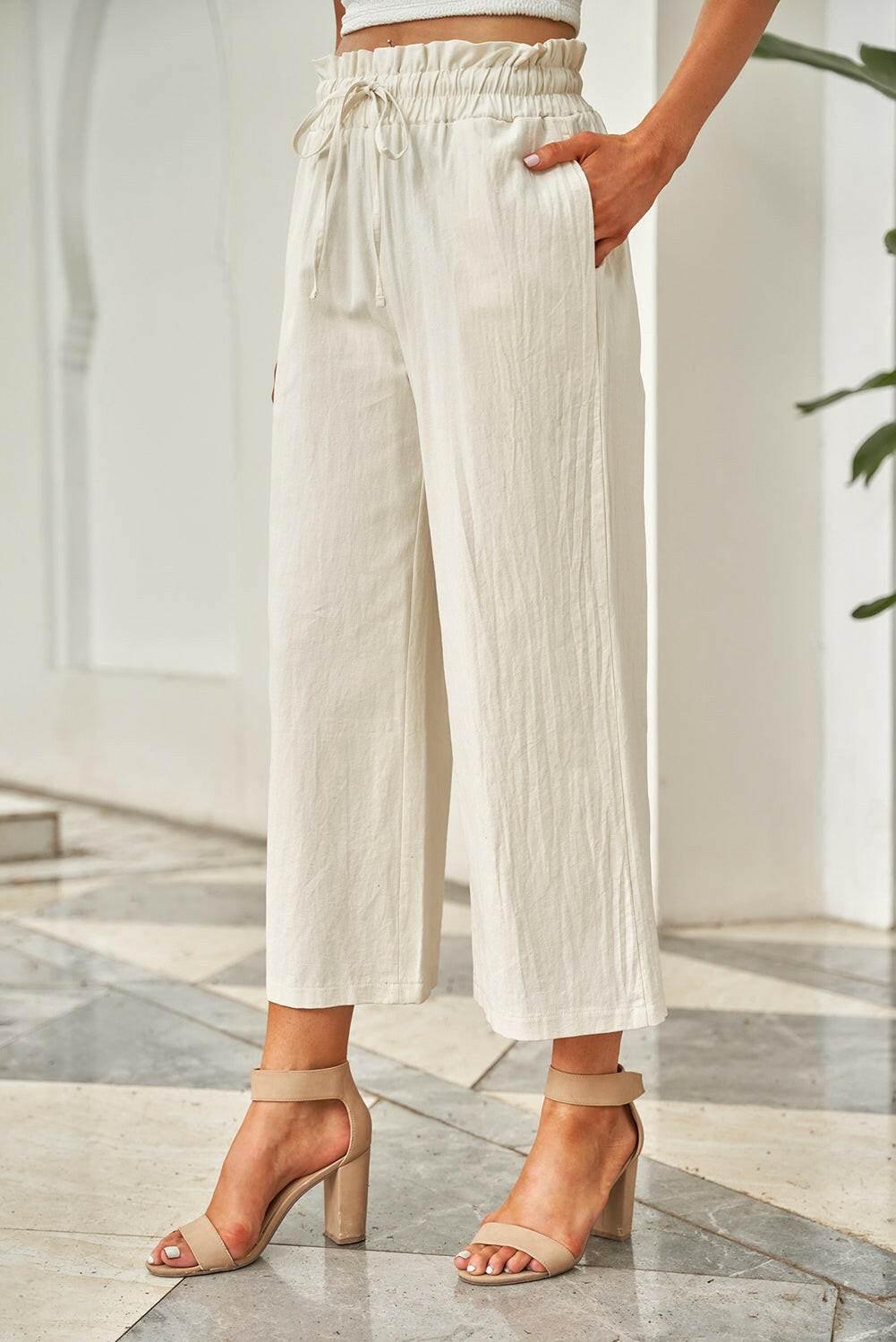 White drawstring paperbag waist wide leg pants made of 100% polyester with an opaque finish and side pockets.