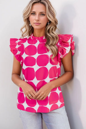 Woman wearing bubblegum pattern frilled collar flutter sleeve top with ruffled shoulders and bold pink circle print