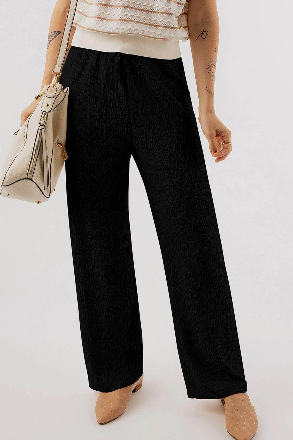 Black textured drawstring straight pants made of soft polyester blend fabric for comfortable all-day wear.