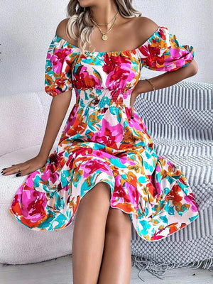 Woman wearing a colorful ruffled hem smocked floral short sleeve midi dress sitting on a chair