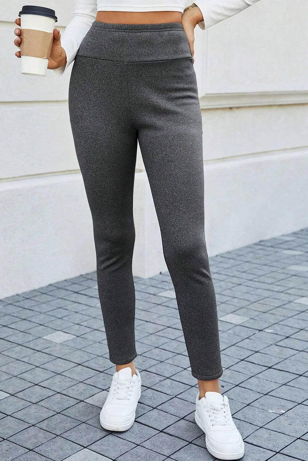 Women wearing charcoal grey high waist leggings with white sneakers and holding a coffee cup outdoors